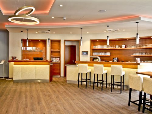 Moderne Hotelbar mit Theke, Barhockern und stilvoller Beleuchtung.