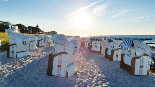 Strandkörbe am Sandstrand mit Sonnenuntergang am Meer.