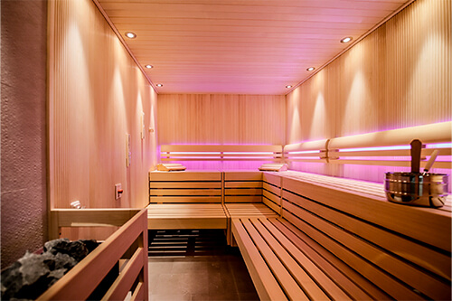 Moderne Sauna aus hellem Holz mit LED-Beleuchtung und Holzbänken.