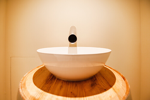 Modernes, rundes Waschbecken auf einer hölzernen Oberfläche mit einem schlichten Wasserhahn.